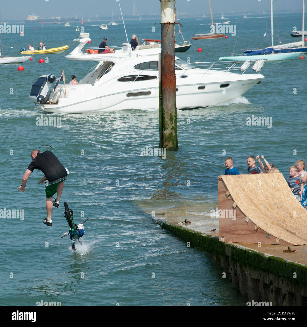 Ciclista con un tuffo nel mare da una rampa di legno. Cowes Regno Unito Inghilterra Foto Stock