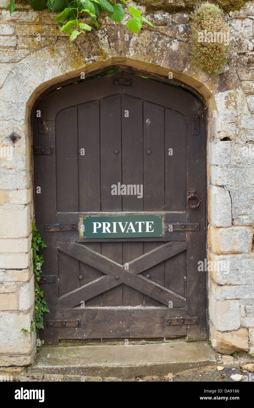 Weathered sportello esterno impostato in un buff di pietra colorata parete. Porta ha segno privato. Foto Stock