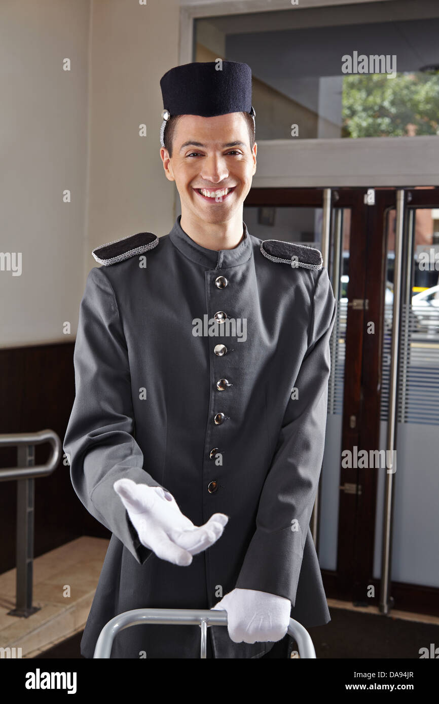 Felice concierge in uniforme in piedi nella hall di un hotel Foto Stock
