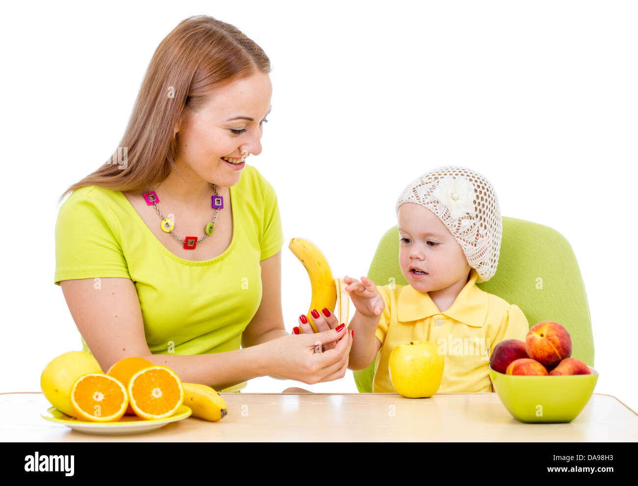 Alimentazione madre bambina con cibo sano seduta a tavola isolato su bianco Foto Stock