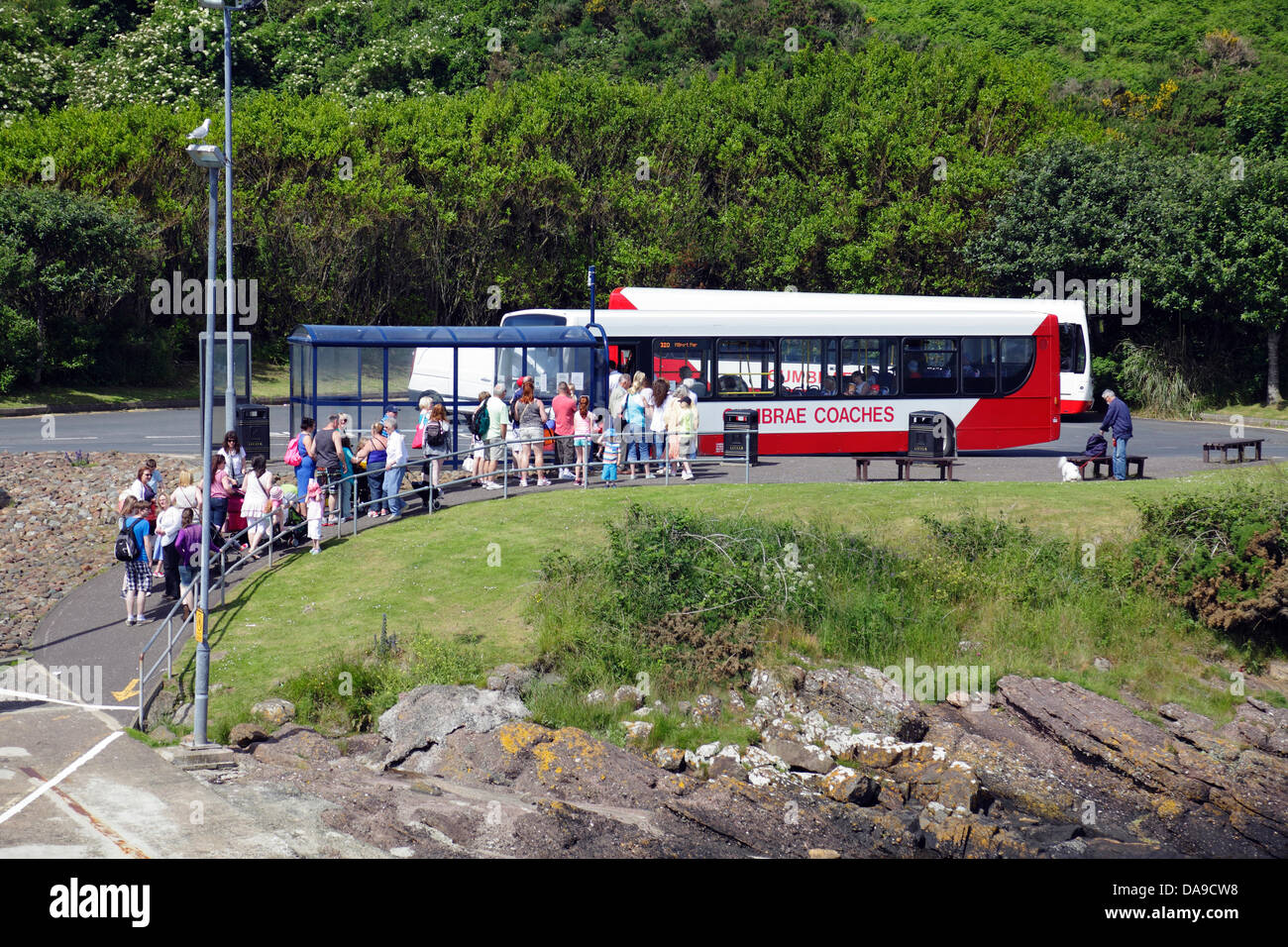 Isola di Gran Cumbrae, Nord Ayrshire, Scozia, Regno Unito, Lunedi, 8 luglio, 2013. I passeggeri sotto il sole caldo aspettano di salire a bordo di un autobus per la città di Millport dopo aver navigato sul traghetto dalla città di Largs nel Firth di Clyde Foto Stock