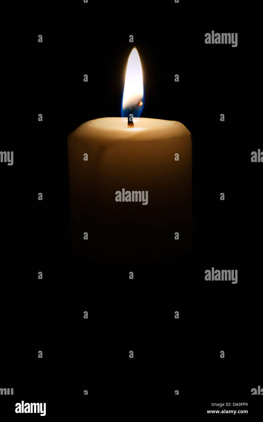 La luce di una candela che mostra di fiamma contro uno sfondo nero Foto Stock