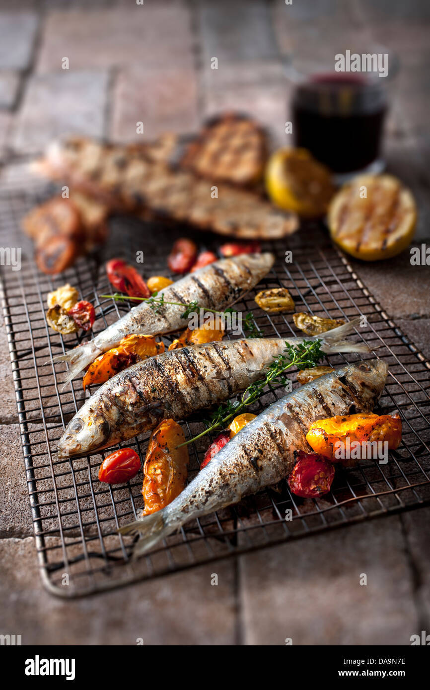 Tutto il pesce alla griglia e colorata di peperoni alla griglia su un rack in metallo Foto Stock