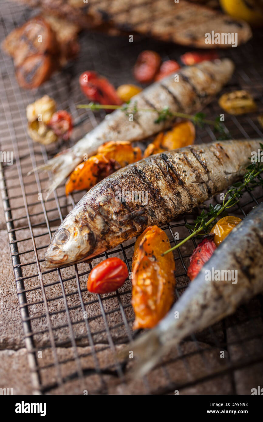 Tutto il pesce alla griglia e colorata di peperoni alla griglia su un rack in metallo Foto Stock