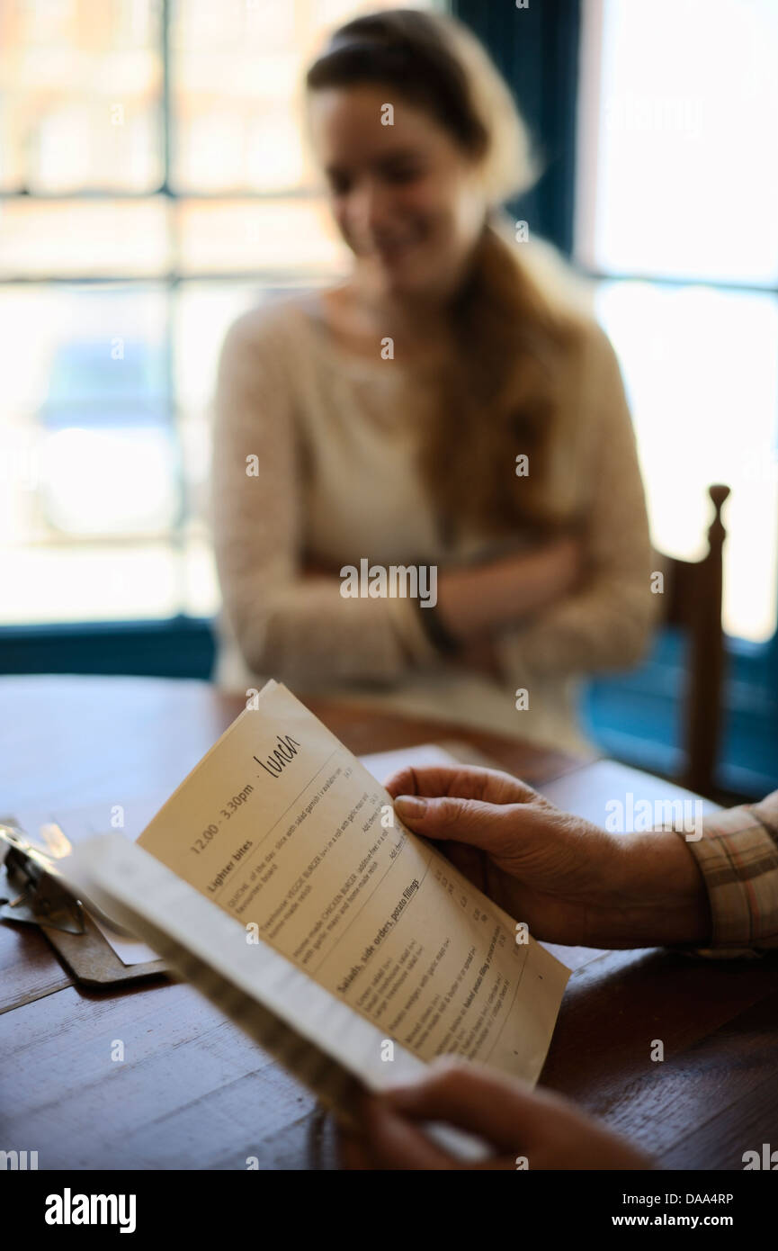 Giovane donna con sua nonna scegliendo da un menu nella finestra sedi in un ristorante a pranzo, Wales, Regno Unito Foto Stock