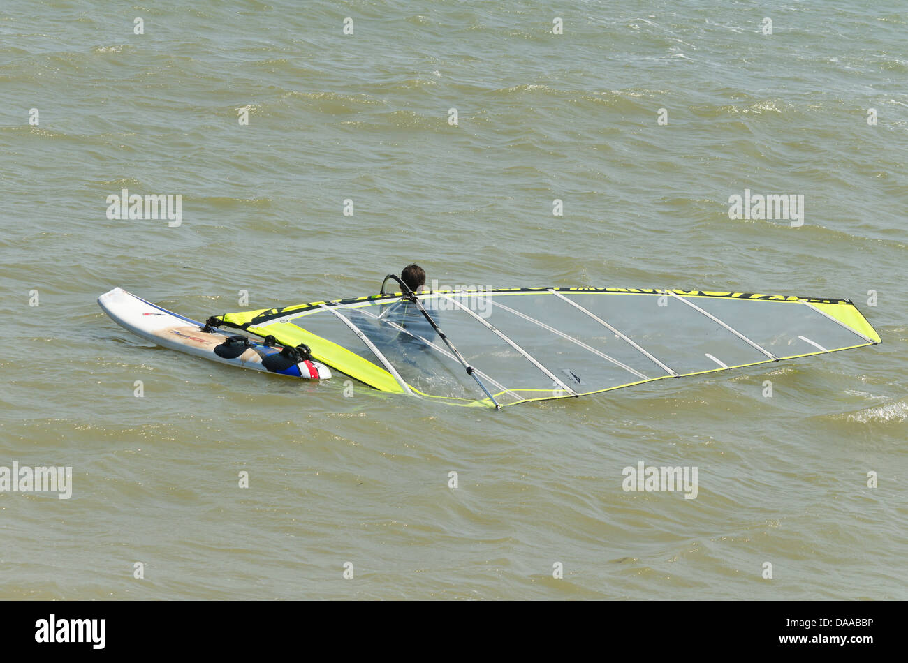 Uomo in mare con la sua tavola a vela Foto Stock