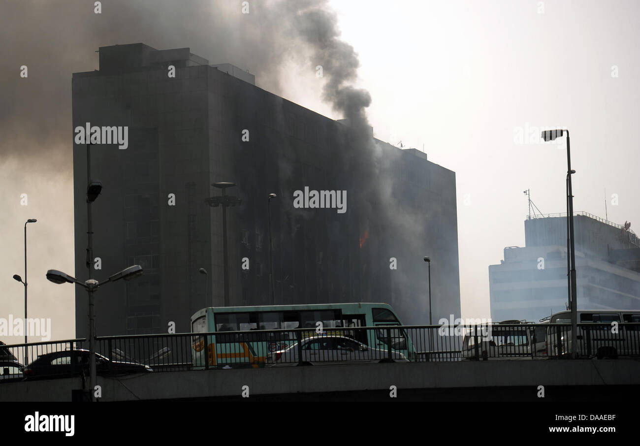 Eminates fumo dal bruciato edificio sede del "National Democratic Party", il partito di governo d'Egitto il Presidente egiziano Hosni Mubarak al Cairo, Egitto, 29 gennaio 2011. Ampia diffusione saccheggi e disordini hanno continuato in Egitto il capitale questo sabato. Le testimonianze oculari ha raccontato del saccheggio di negozi in corso, mentre in due distretti del Cairo, le stazioni di polizia sono state assaltata da Foto Stock