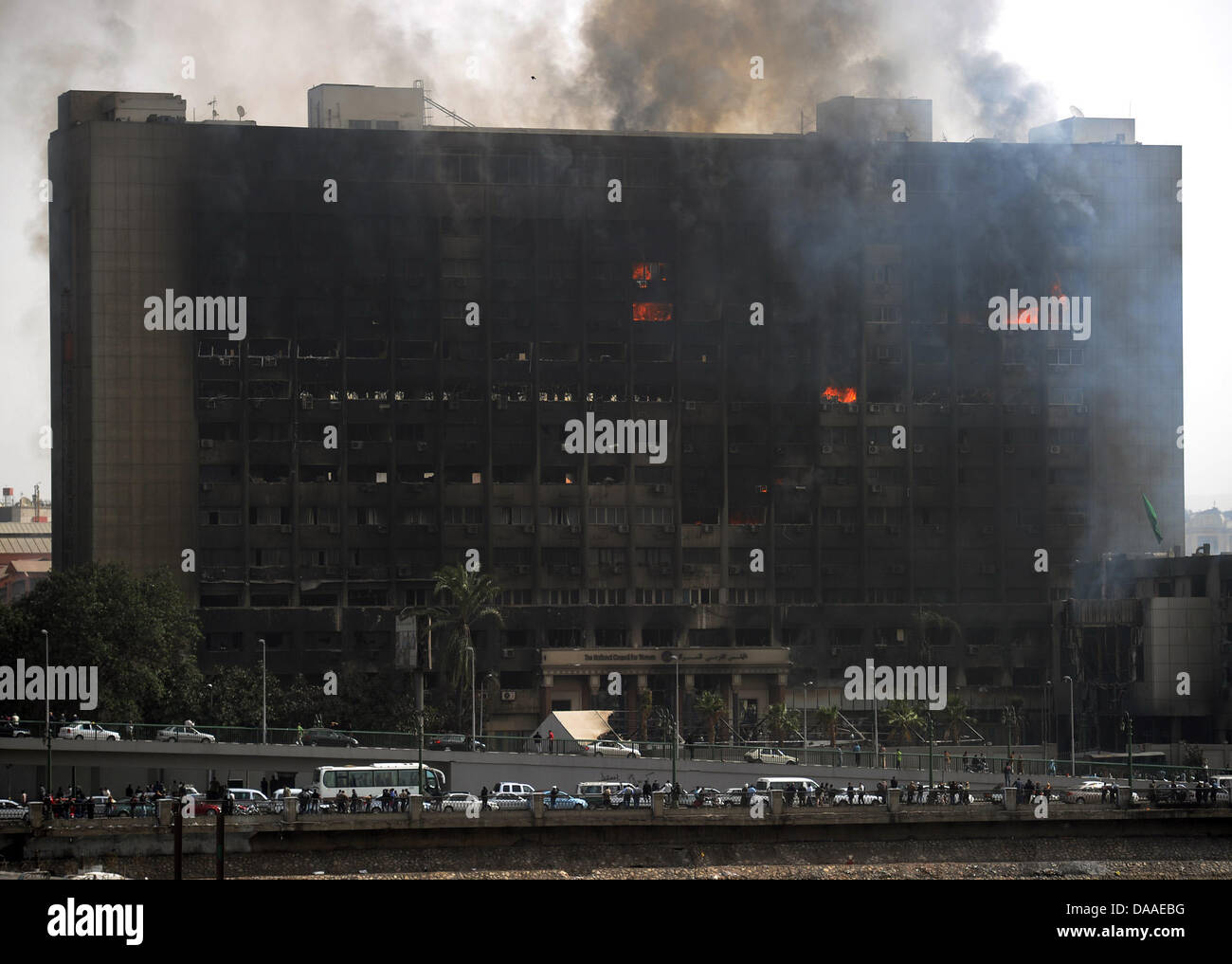 Eminates fumo dal bruciato edificio sede del "National Democratic Party", il partito di governo d'Egitto il Presidente egiziano Hosni Mubarak al Cairo, Egitto, 29 gennaio 2011. Ampia diffusione saccheggi e disordini hanno continuato in Egitto il capitale questo sabato. Le testimonianze oculari ha raccontato del saccheggio di negozi in corso, mentre in due distretti del Cairo, le stazioni di polizia sono state assaltata da Foto Stock