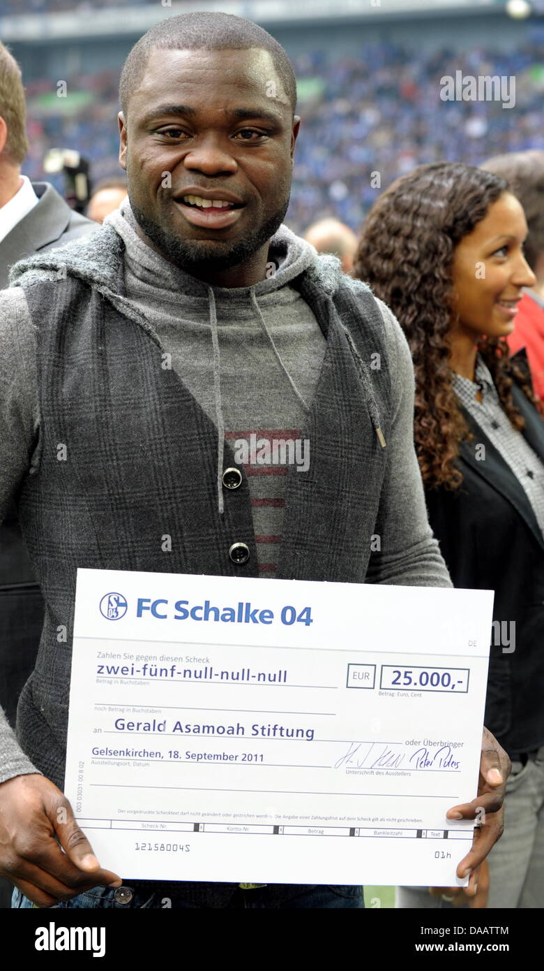 L'ex giocatore di Schalke, Gerald Asamoah, reveives un controllo con 25 000 euro da FC Schalke per la sua fondazione prima della Bundesliga tedesca partita FC Schalke 04 rispetto a FC Bayern Monaco presso la VeltinsArena a Gelsenkirchen (Germania), 18 settembre 2011. Foto: Federico Gambarini Foto Stock