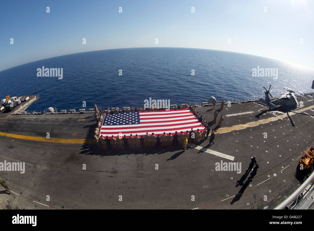 Marinai e Marines visualizzare il ensign nazionale in onore del giorno di indipendenza a bordo dell'assalto anfibio nave USS Kearsarge ( Foto Stock