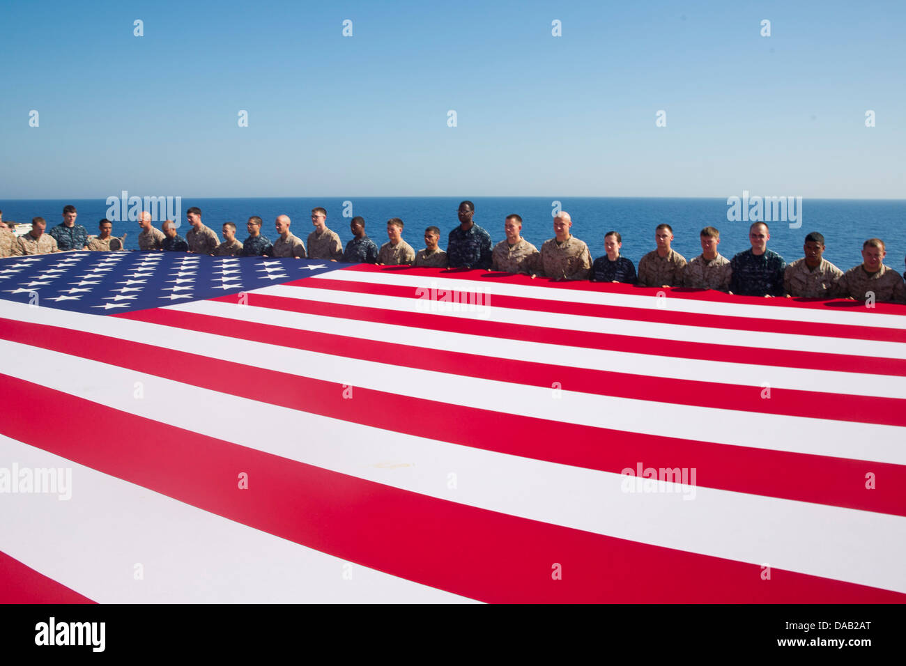 Marinai e Marines visualizzare il ensign nazionale in onore del giorno di indipendenza a bordo dell'assalto anfibio nave USS Kearsarge ( Foto Stock