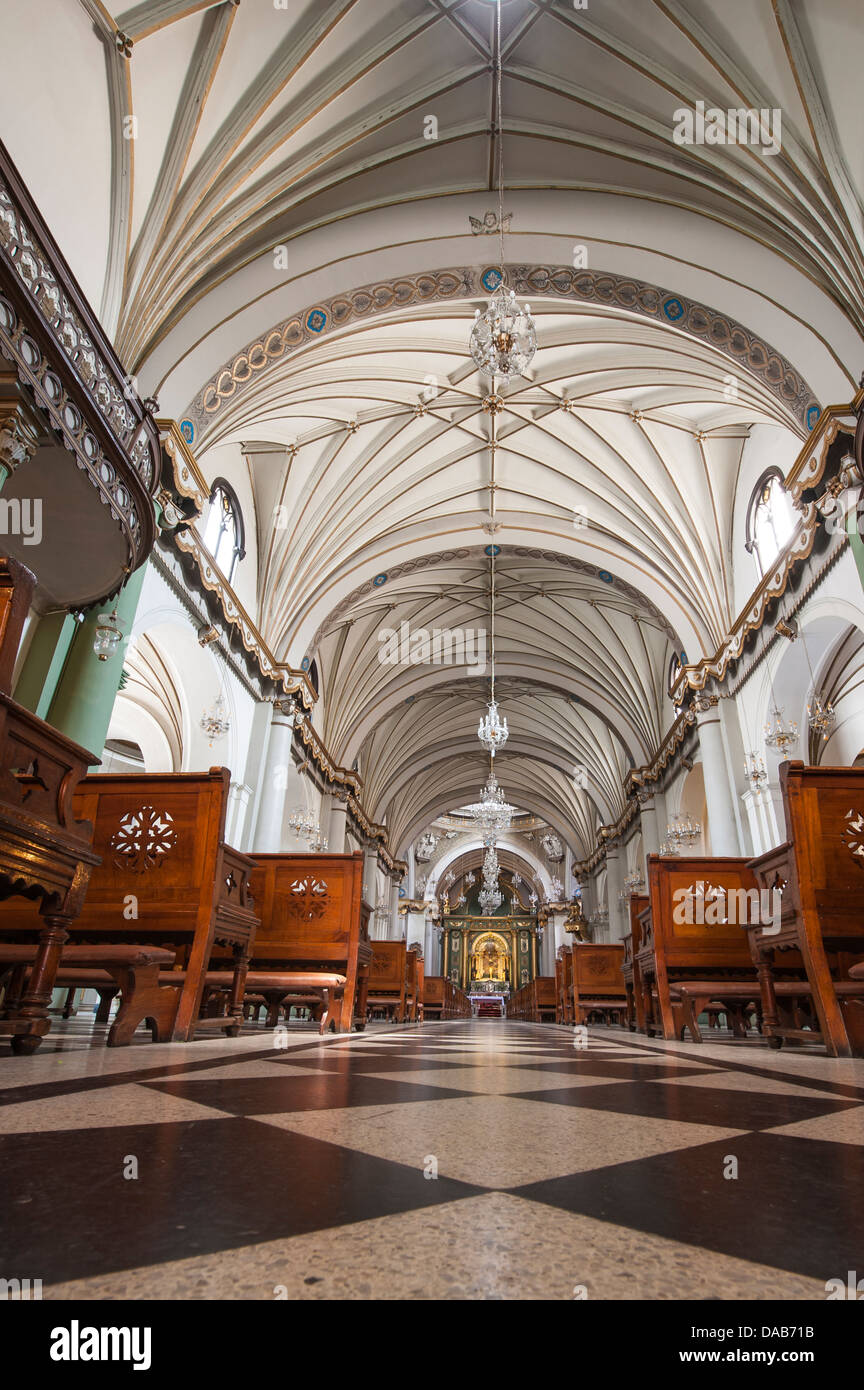 Corridoio pavimento a scacchi soffitto banchi della chiesa cattolica romana e il convento di Santo Domingo, Lima, Perù. Foto Stock