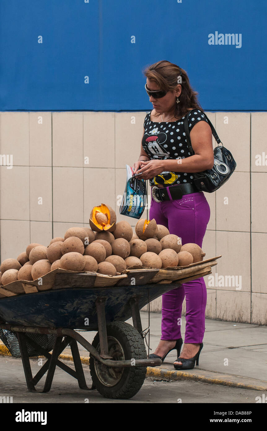 Donna acquisto compra noci di cocco cocco da un marciapiede di strada fornitore nel centro di Trujillo, Perú. Foto Stock