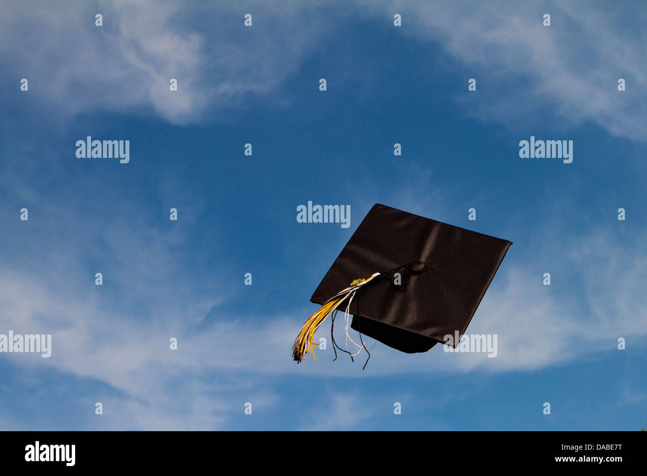 Tappo di graduazione volare attraverso l'aria a una cerimonia di laurea contro un cielo blu con nuvole bianche, con successo il volo libero! Foto Stock