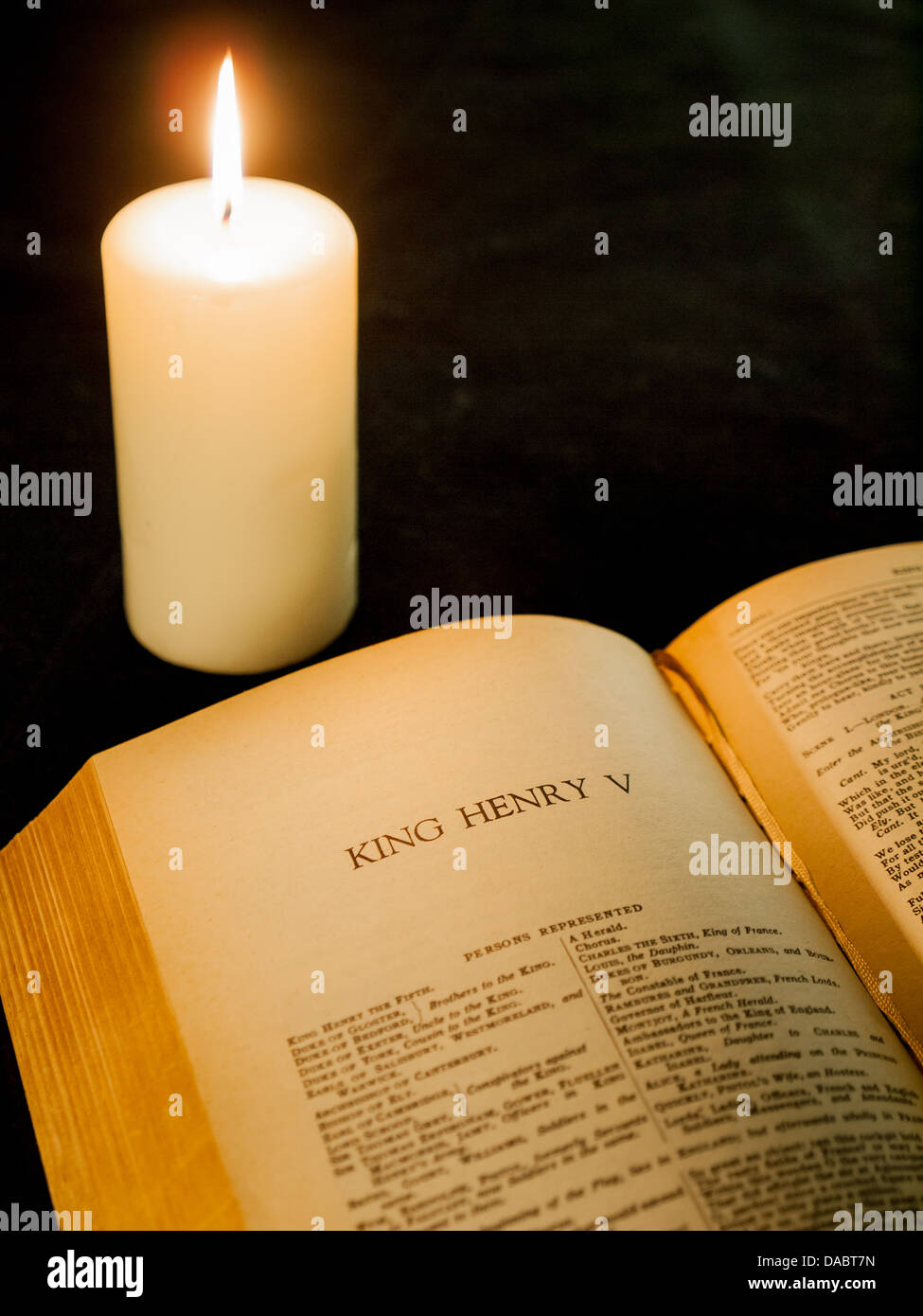 Una vecchia copia di le opere complete di Shakespeare aperto sulla prima pagina del re Enrico V. una singola candela che brucia visble dietro . Foto Stock