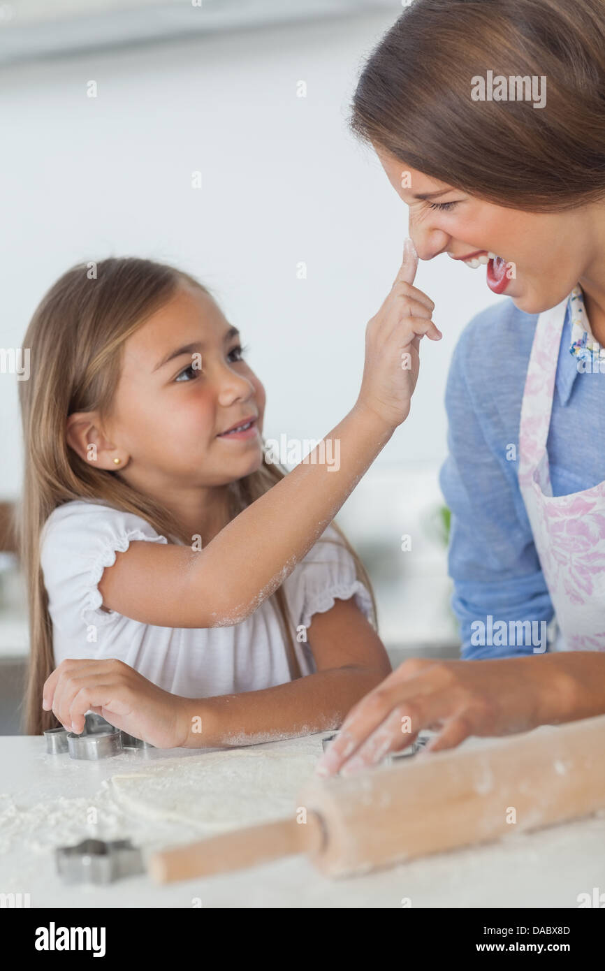 Bambina di mettere la farina sul naso di sua madre Foto Stock