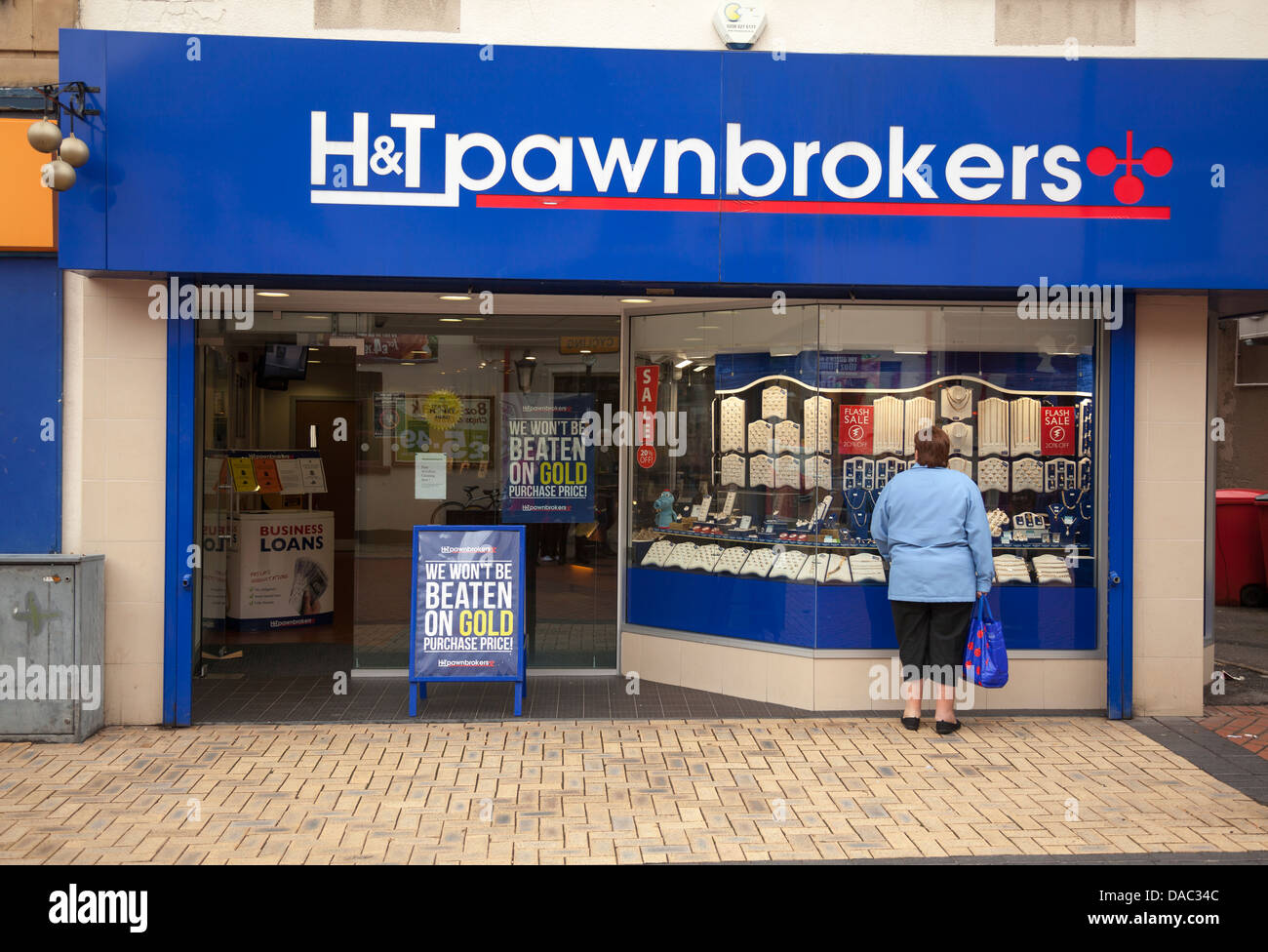 Donna che guarda nella finestra di Pawnbrokers a Worksop, Nottinghamshire, Inghilterra Foto Stock
