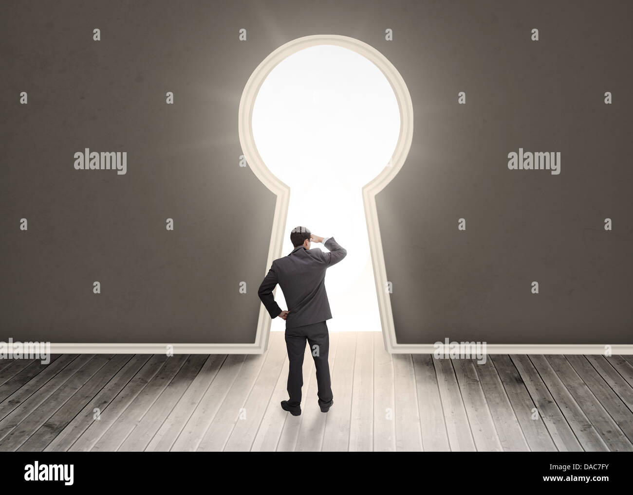 Imprenditore guardando attraverso il buco della serratura della porta di forma Foto Stock