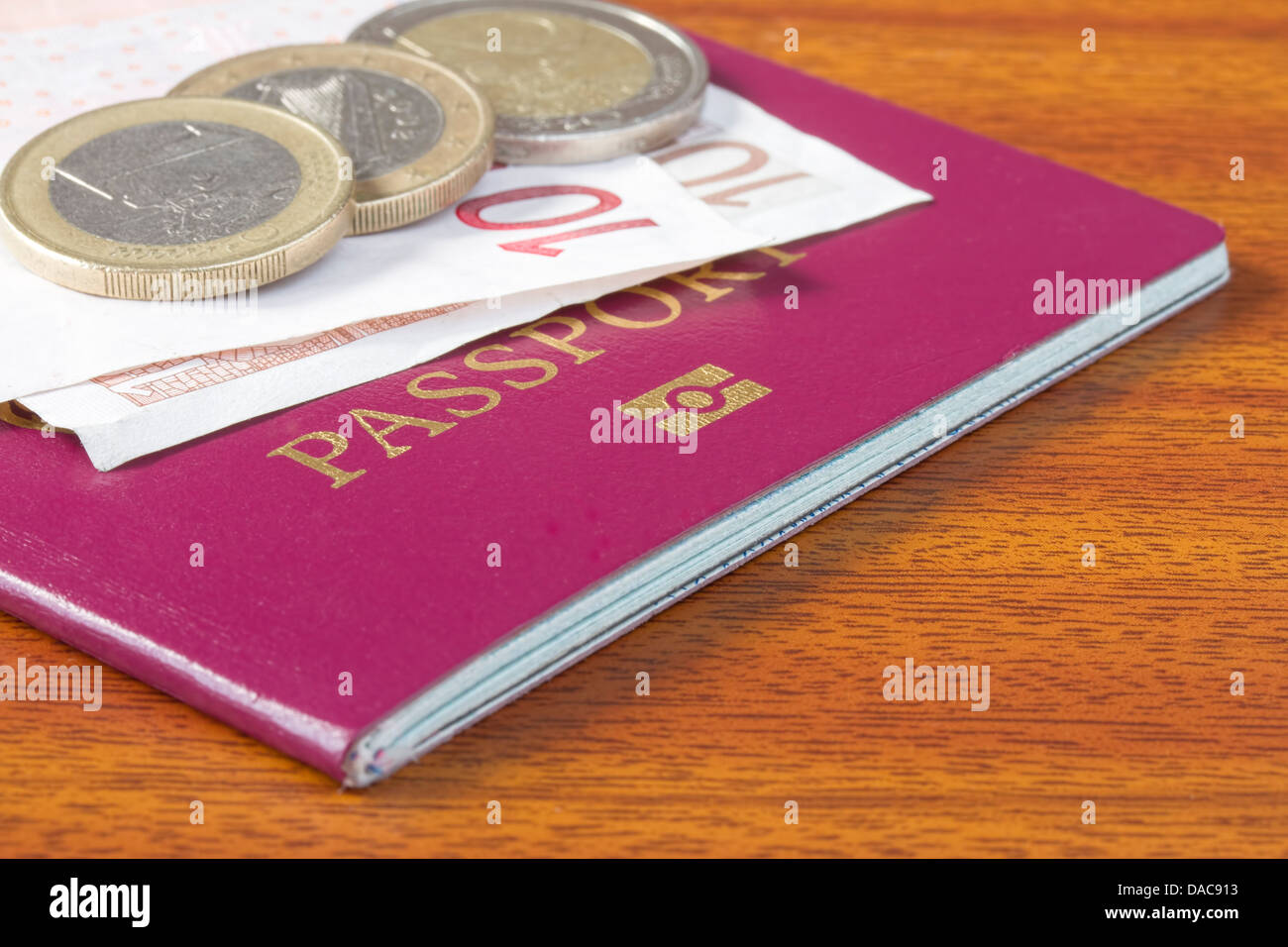 Passaporto britannico con monete e banconote in euro sul tavolo di legno Foto Stock