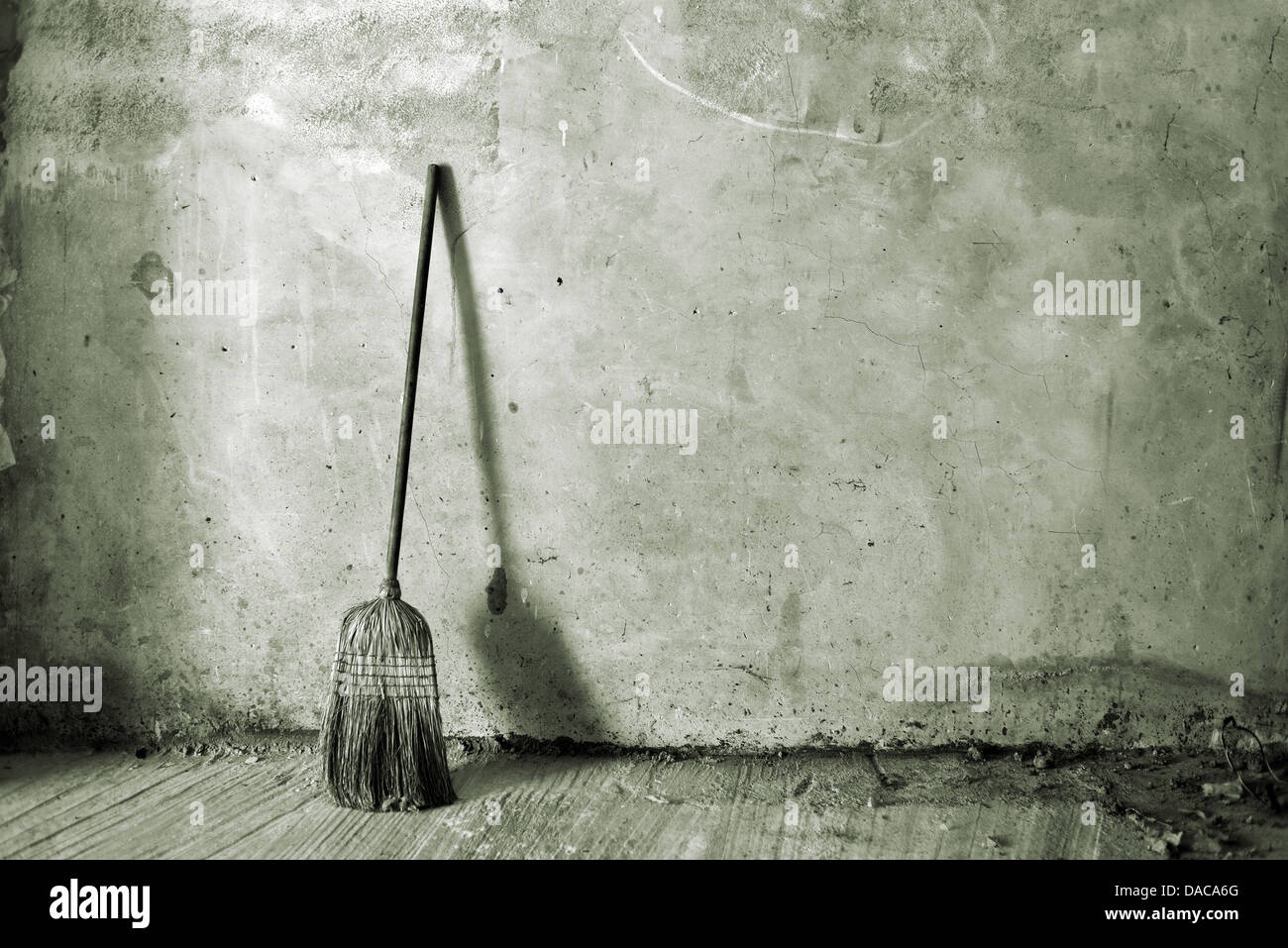 Vecchia scopa obsoleti o besom appoggiata al muro grigio Foto Stock