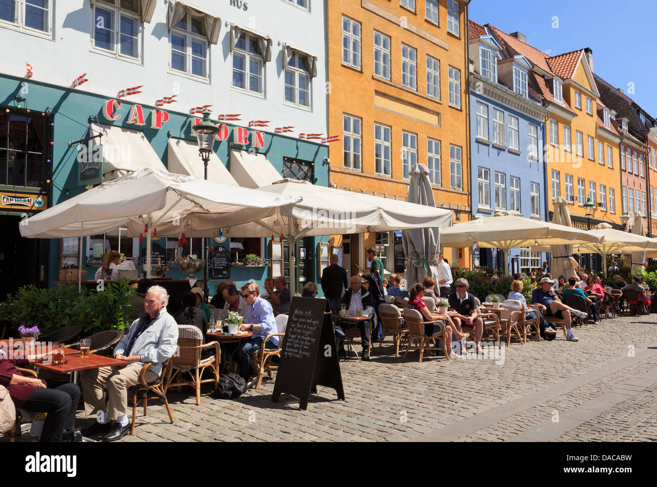 Caffetterie all'aperto con persone cenare fuori a godersi il sole sulla strada pedonale di Nyhavn, Copenaghen, Zelanda, Danimarca Scandinavia Foto Stock