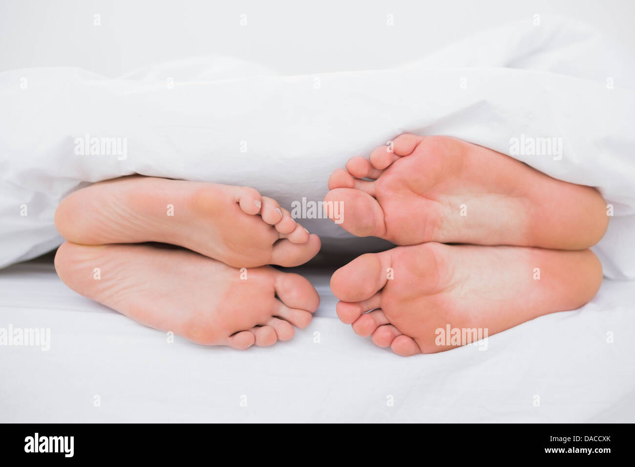 I piedi di un giovane faccia a faccia nel letto Foto Stock