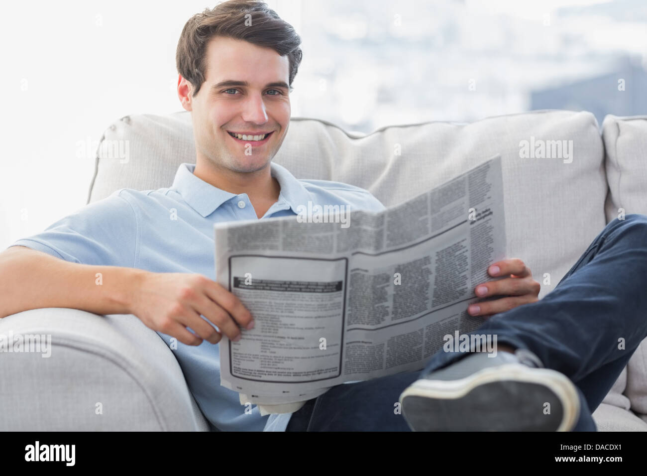 L'uomo leggendo un giornale seduto su un divano Foto Stock