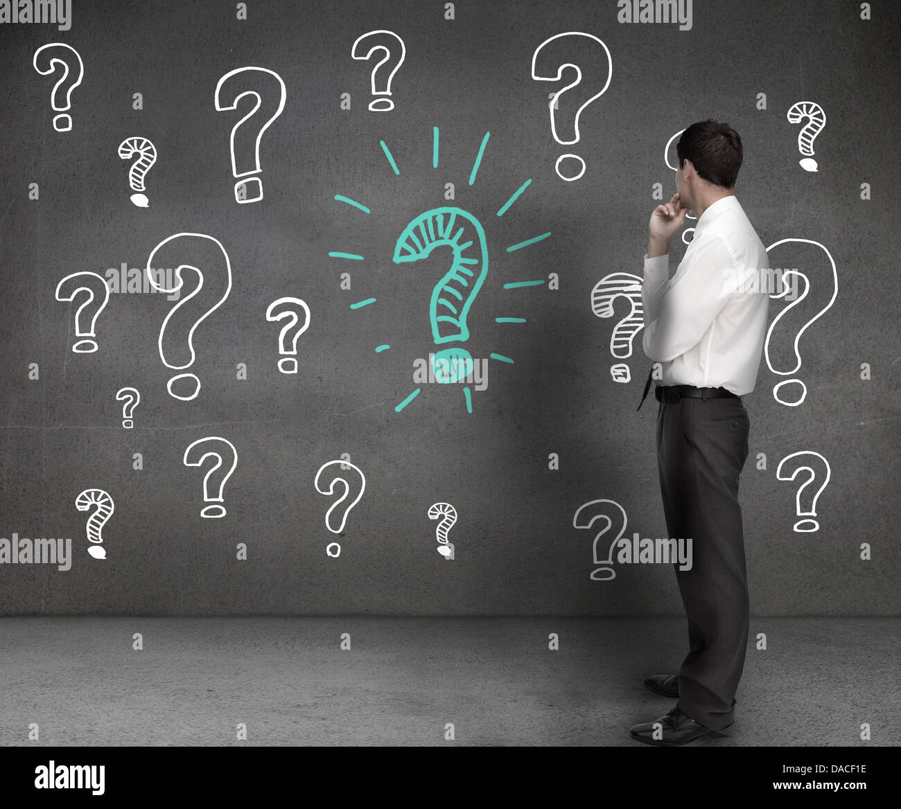 Imprenditore guardando i disegni dei punti interrogativi Foto Stock