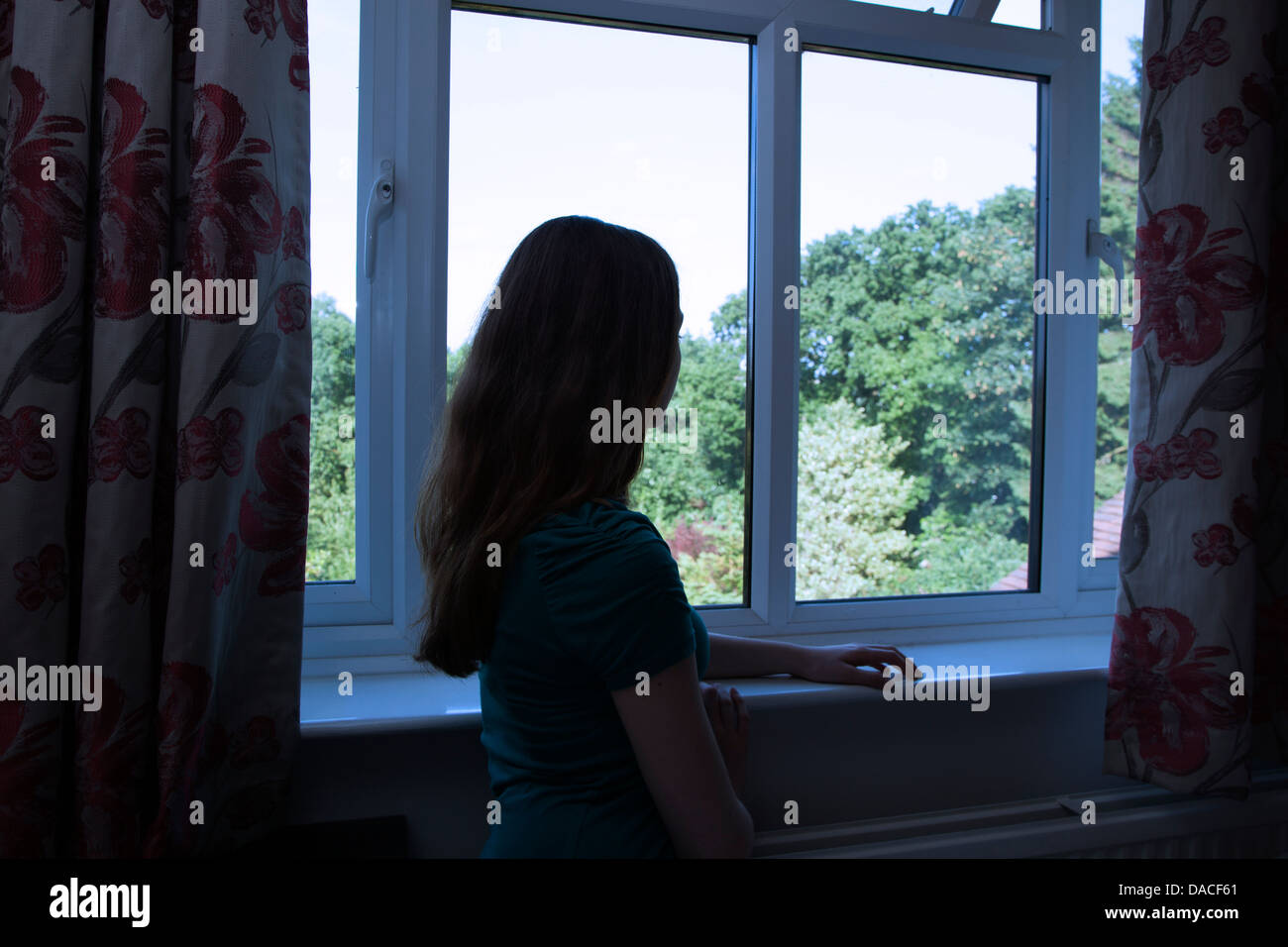Una ragazza adolescente, guardando fuori della finestra. Posteriore/vista laterale. Foto Stock