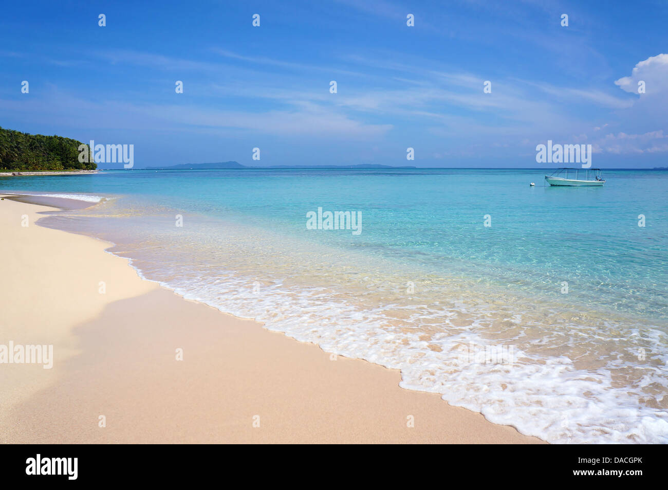 Bella spiaggia tropicale con acqua chiara e una barca da soli nel mar dei Caraibi Foto Stock