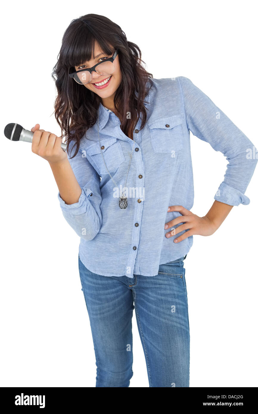 Carino donna con la sua mano su hip tenendo il microfono Foto Stock
