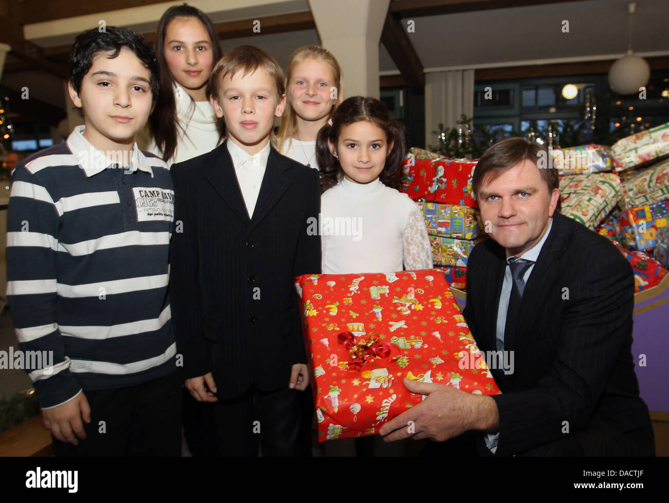 Il Ministro degli interni della Bassa Sassonia Uwe Schuenemann (CDU) pone con i regali di Natale e figli di emigranti e richiedenti asilo durante una festa di Natale presso il campo di transito Friedland vicino a Goettingen, Germania, 15 dicembre 2011. Il campo di transito più e più perde la sua funzione come un intermedio alloggio camp per gli emigranti. Solo circa 2200 tedeschi etnici provenienti da paesi di t Foto Stock