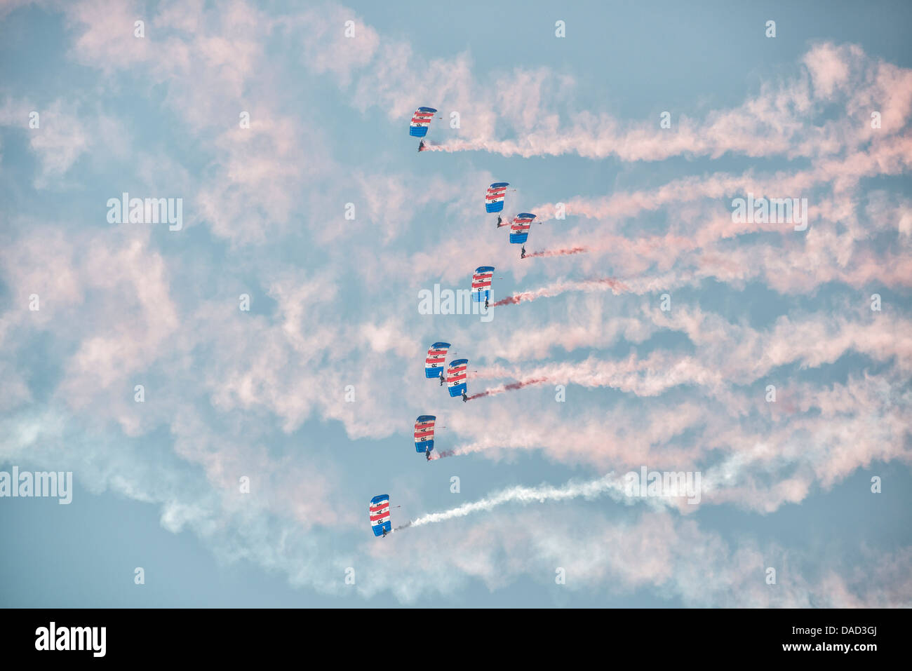 Skydivers dalla Royal Air Force Falcons team display riempiono il cielo con i loro paracadute colorato tettoie e sentieri di fumo. Foto Stock