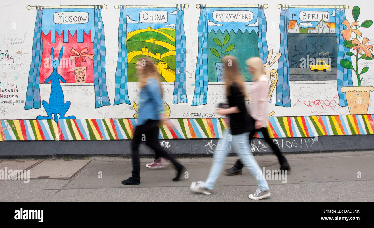 Le giovani donne a piedi lungo la East Side Gallery di Berlino, Germania, 11 luglio 2013. La East Side Gallery è il più grande del mondo aperto e permanente galleria aria sulla lunga preservato il resto del muro di Berlino in Muehlenstraße tra stazione di Berlin Ostbahnhof e Oberbaumbruecke ponte accanto al fiume Sprea. Foto: MARCEL KUSCH Foto Stock