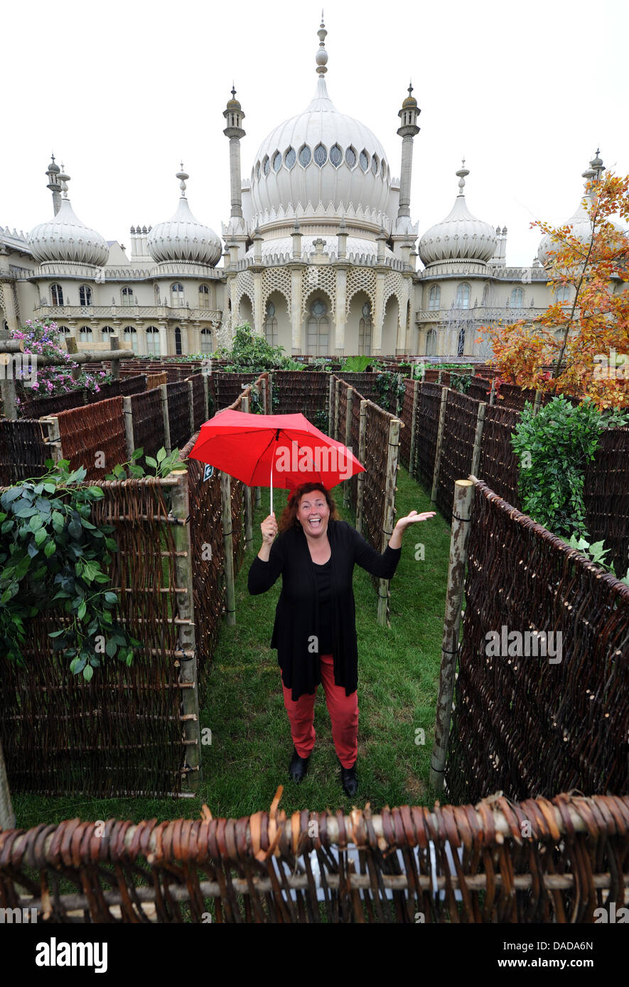 Donna con ombrello rosso perso nel labirinto gigante presso il Royal Pavilion Brighton Regno Unito Foto Stock