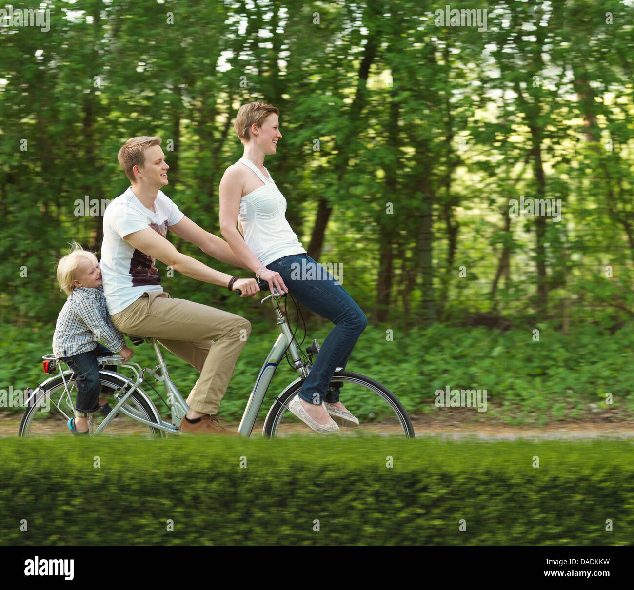 Famiglia con un bambino correre sulla bicicletta insieme Foto Stock