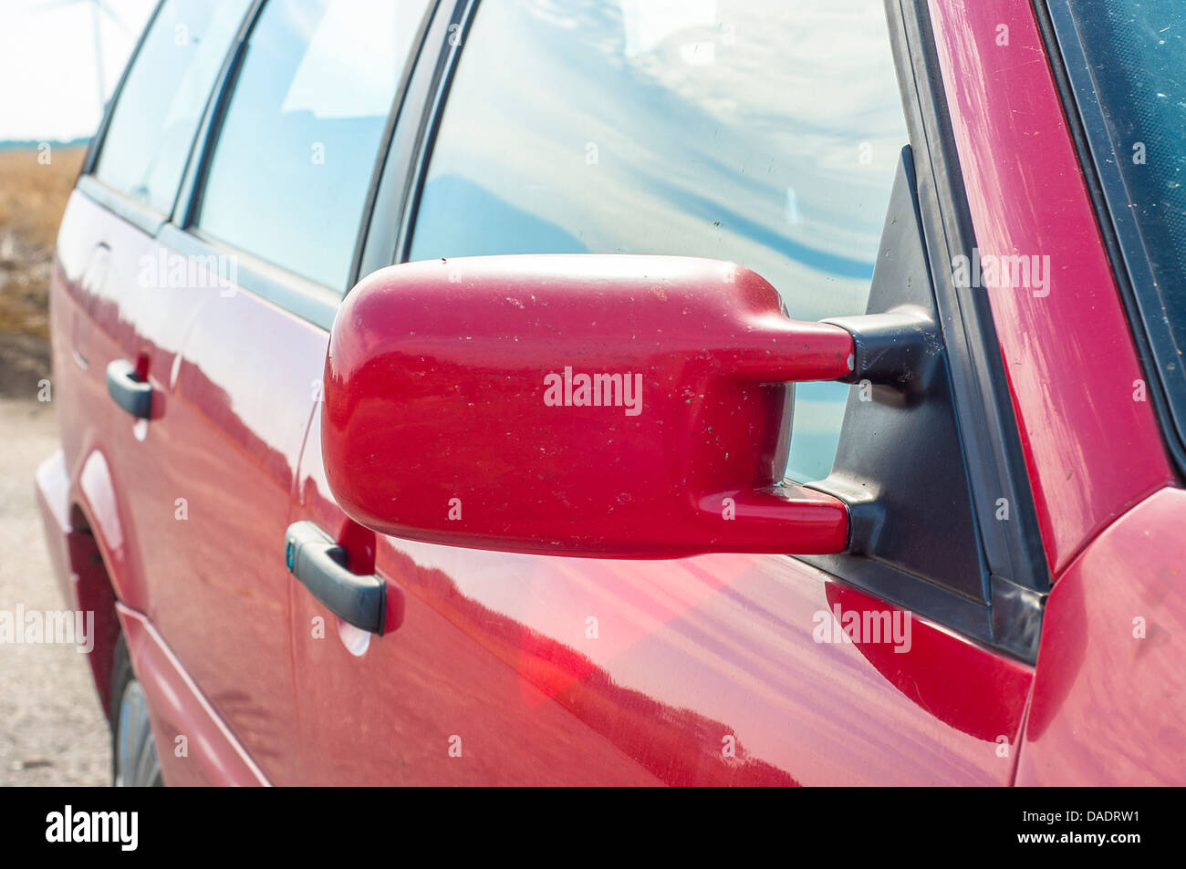 Auto rossa e specchio di riflessione di mulino a vento sulla finestra Foto Stock