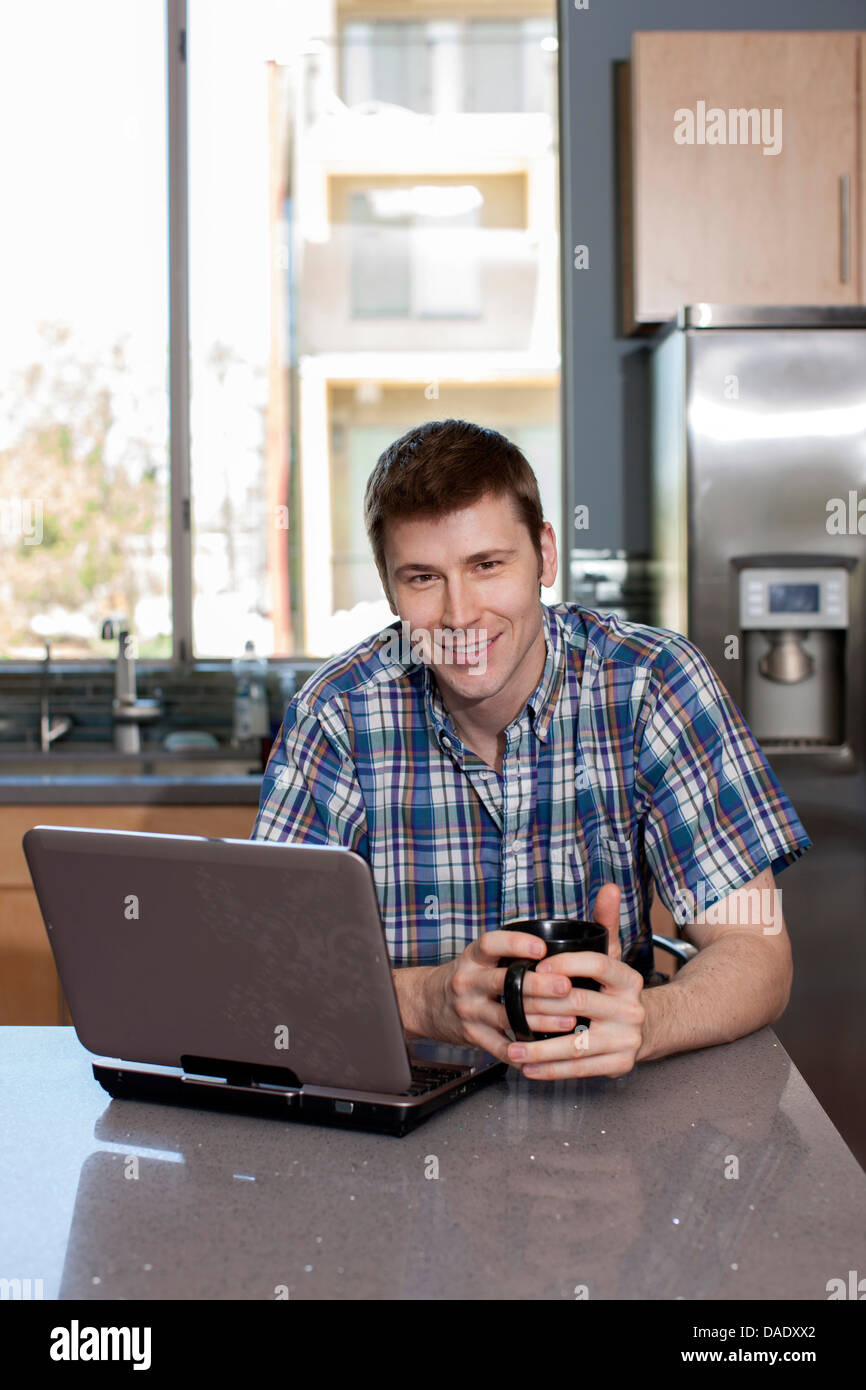 Metà uomo adulto utilizzando laptop in cucina, ritratto Foto Stock