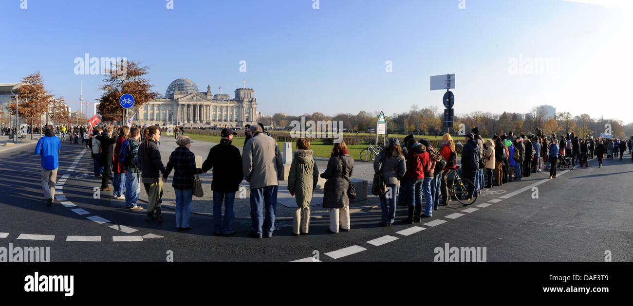 Manifestanti formano una catena umana di fronte al Reichstag di Berlino, Germania, 12 novembre 2011. Lo slogan della protesta organizzata da Campact, Attac, l'associazione tedesca degli amanti della natura e di altri gruppi è " divieto alle banche" (Banken in die Schranken). Una dimostrazione sotto lo stesso nome avviene contemporaneamente in Frankfurt Main. I manifestanti chiedono la rottura di bi Foto Stock