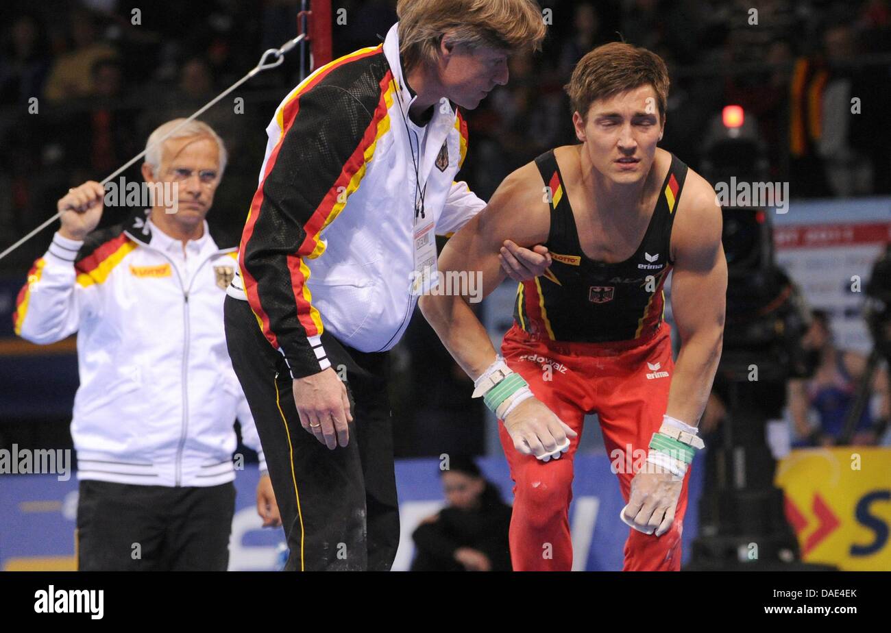Accanto alla testa tedesco coach Andreas Hirsch (L) atleta tedesco Philipp Boy è supportata dopo che è caduto fuori della barra durante la Gymnastics World Cup alla Porsche Arena di Stoccarda, Germania, 13 novembre 2011. Foto: MARIJAN MURAT Foto Stock