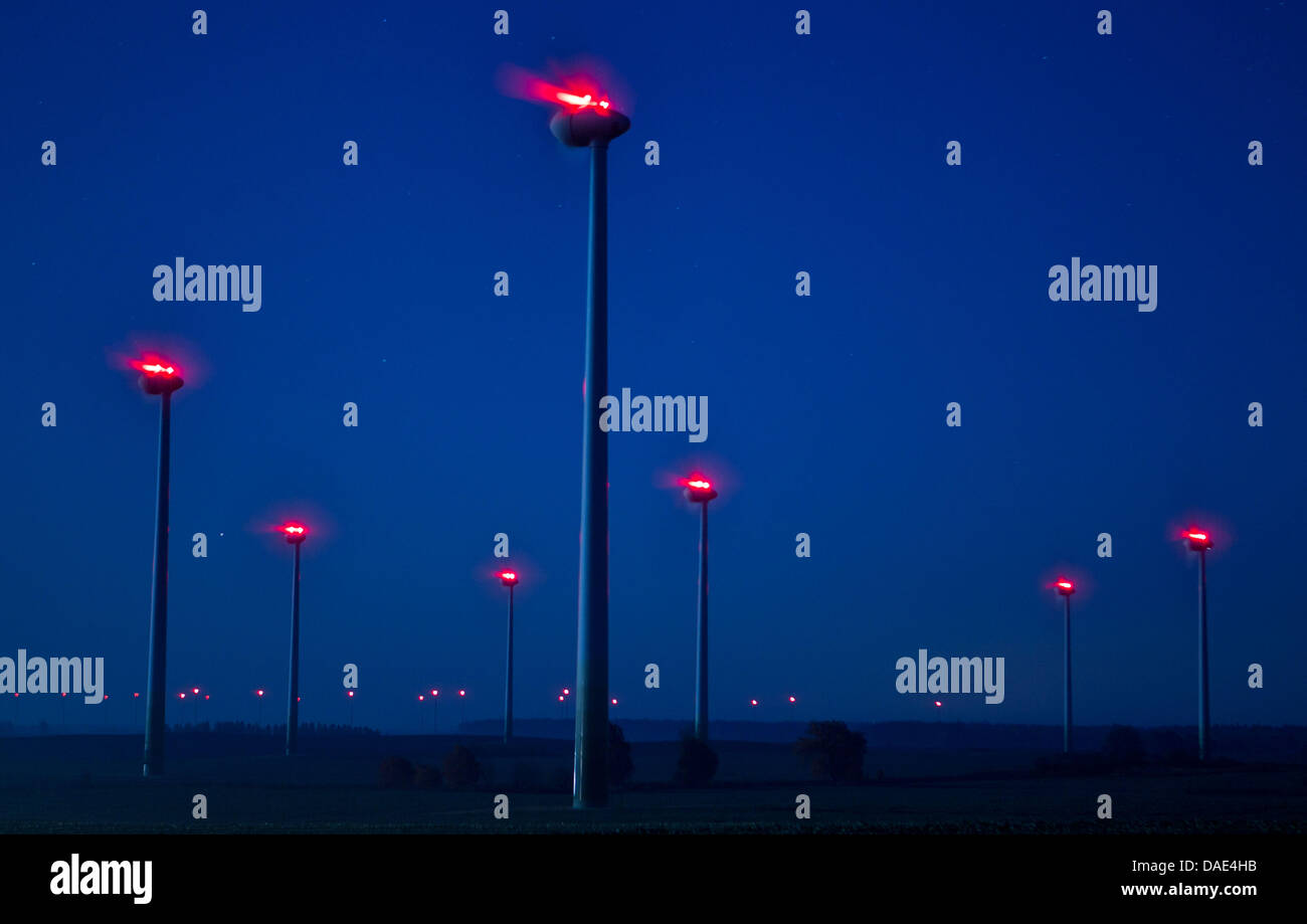 Una turbina eolica con una luce d'ingombro rossa si trasforma in un parco eolico vicino Kladrum, Germania, 10 novembre 2011. La rotazione dei rotori può difficilmente essere visto a causa del lungo tempo di esposizione, solo la luce rossa di riflessioni può essere visto. A causa dell'assenza di linee di potenza e la minaccia della griglia di alimentazione sovraccarico, più e più parchi eolici devono essere obbligatoriamente spenti. La arresti hanno quasi fare Foto Stock