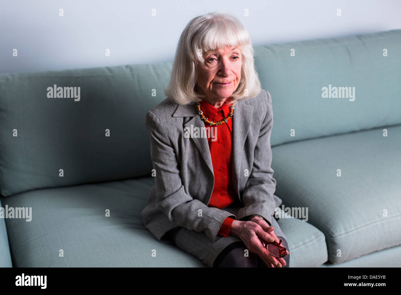 Senior donna seduta su un divano con espressione vuota Foto Stock