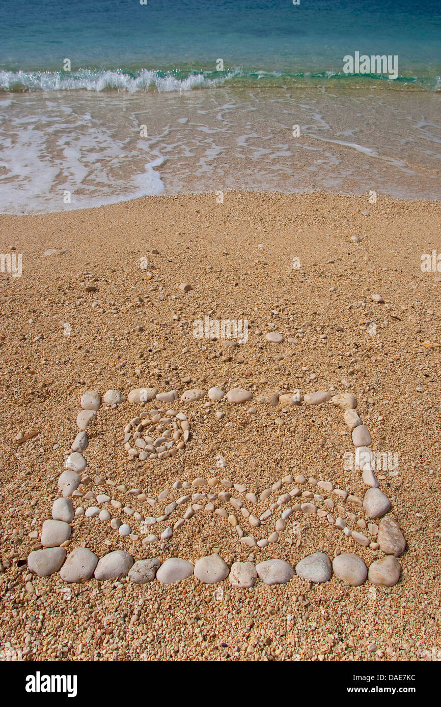 Mosaik fatta di pietre nella sabbia al mare Mediterraneo che mostra il sole sulle onde del mare, Italia, Sicilia Foto Stock