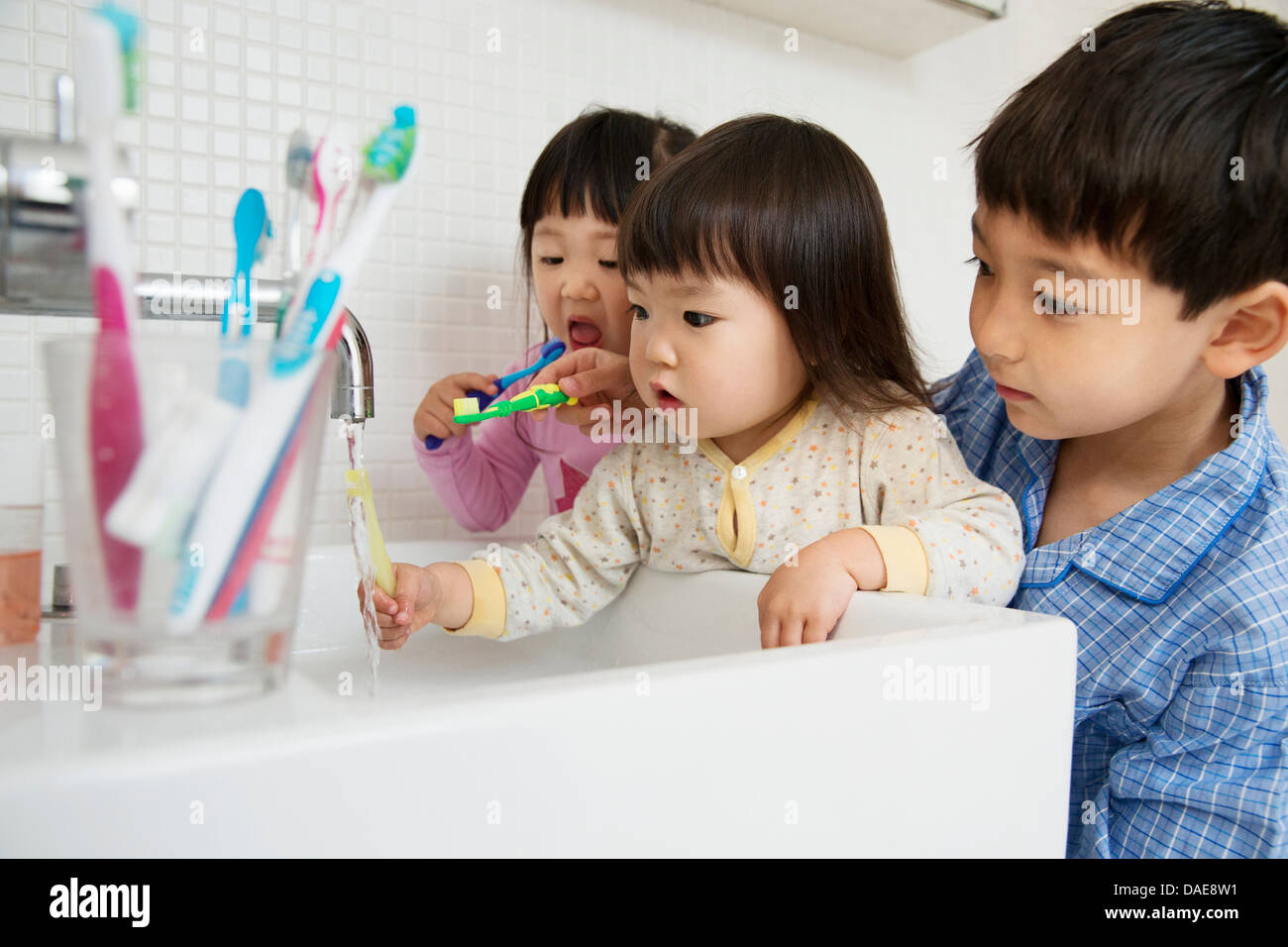 Fratello aiutare le sorelle a pulire i denti Foto Stock