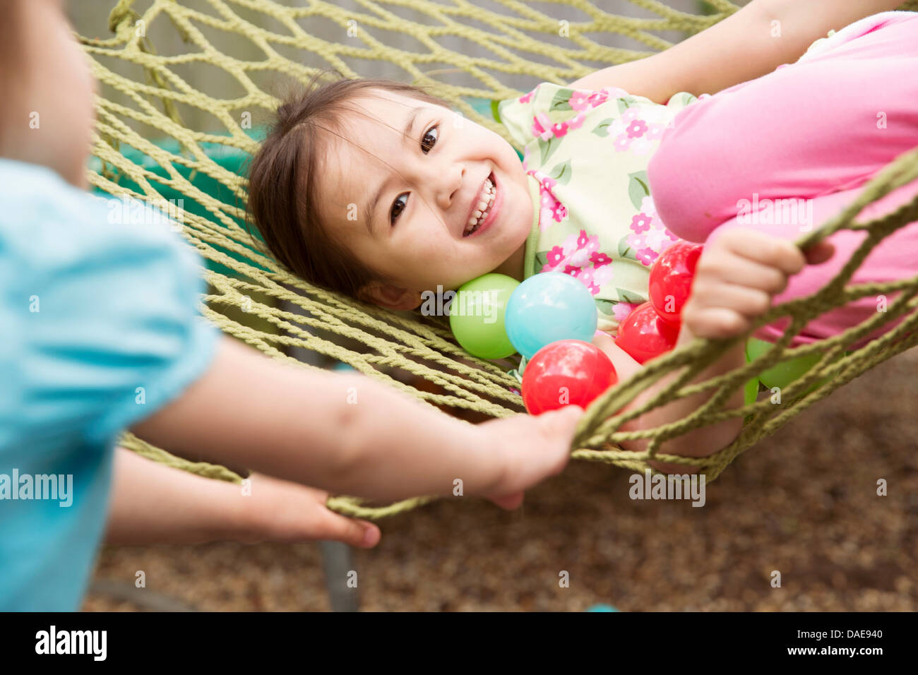 Giovane ragazza in amaca con le palle colorate Foto Stock