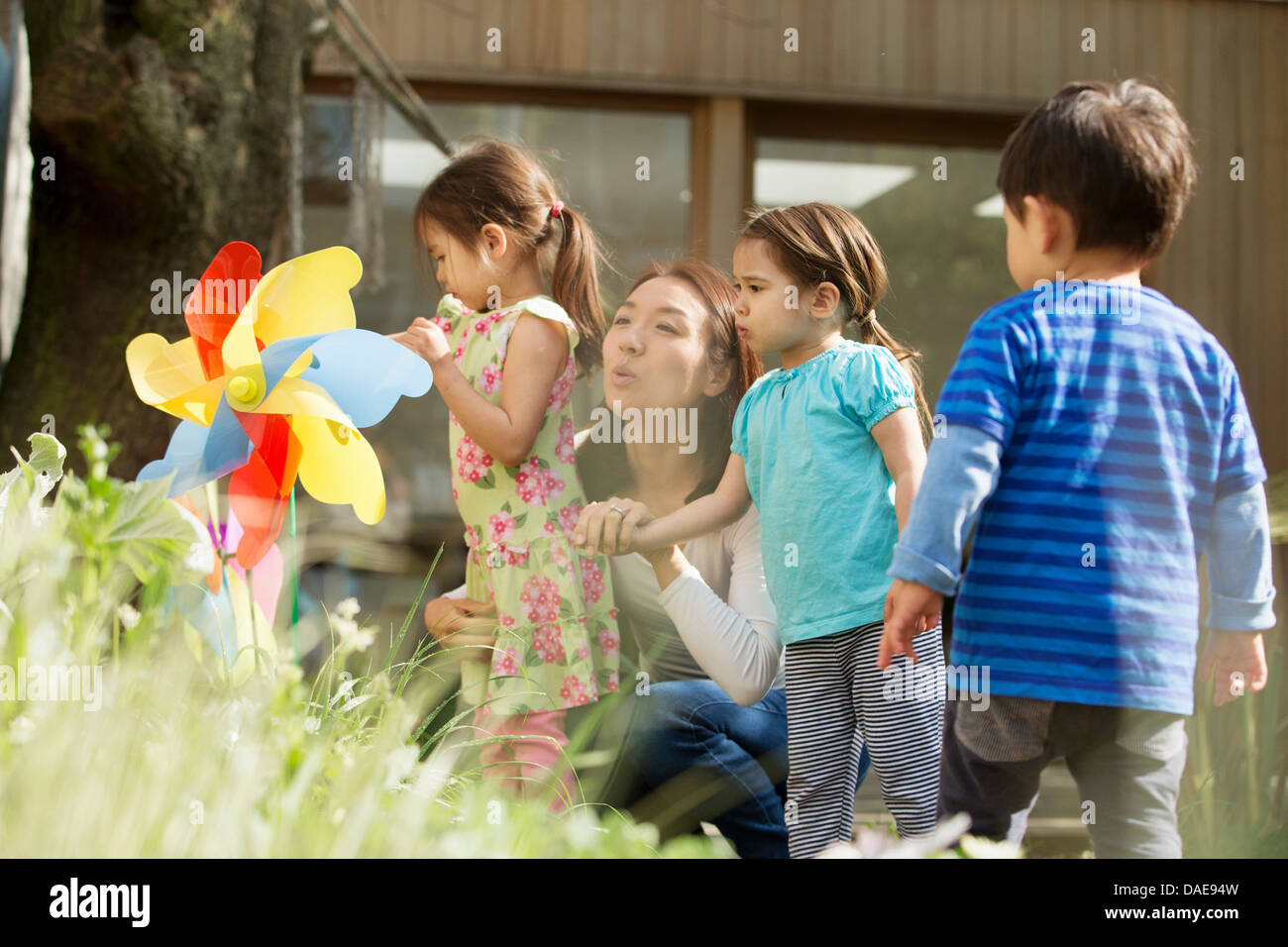 Madre e tre figli con il mulino a vento di giocattolo in giardino Foto Stock