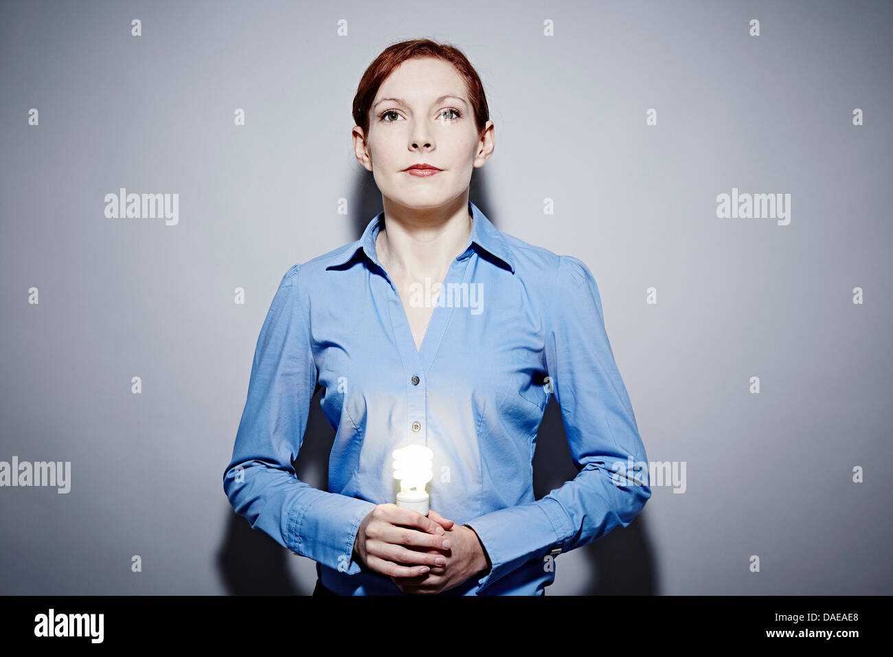 Studio Ritratto di giovane donna d'affari tenendo accesa lampadina Foto Stock