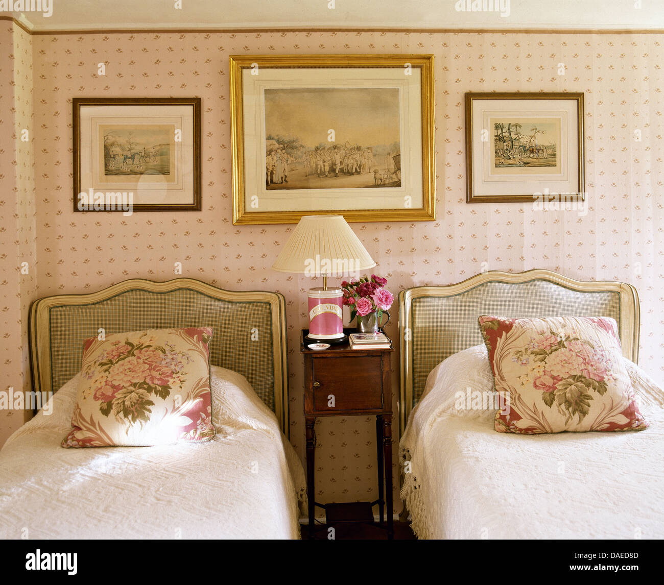 Foto sopra imbottiti letti singoli con rose cuscini modellato e coperchi di colore bianco in cottage camera da letto con carta da parati rosa Foto Stock