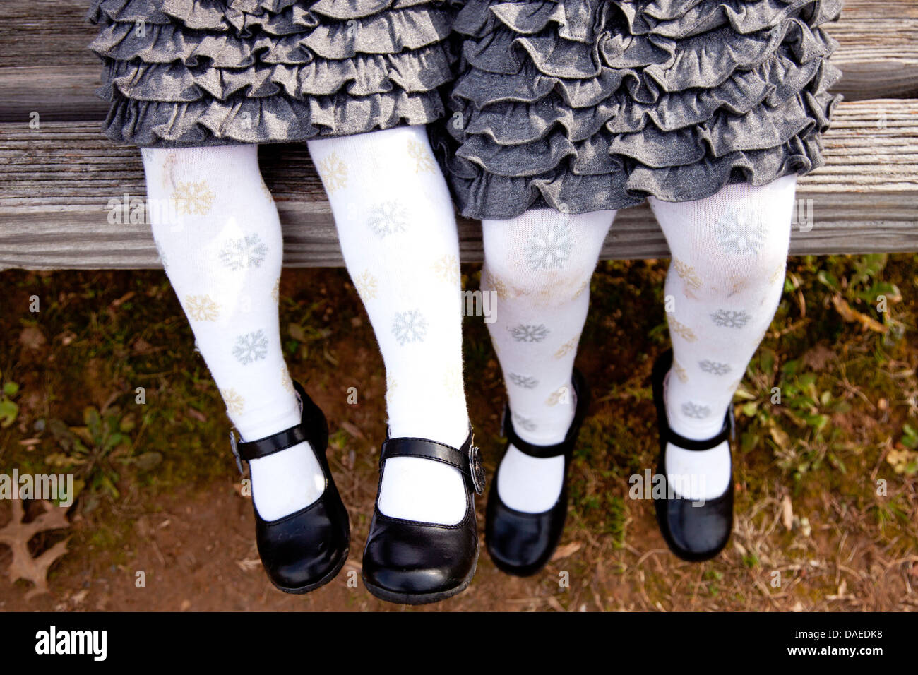 Due ragazze in corrispondenza abbigliamento gambe penzolanti sul banco di lavoro Foto Stock