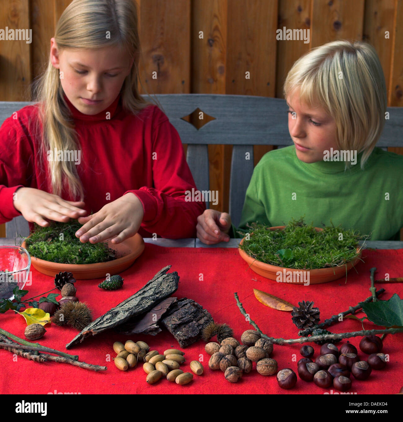 Due bambini ritocchi di una nana giardino con materiali di natura, Germania Foto Stock